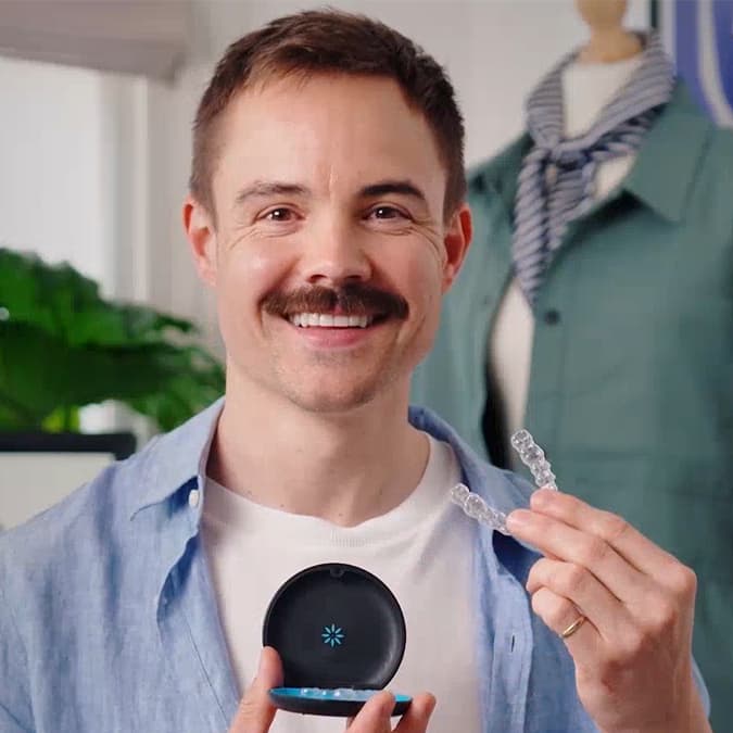 Man smiling and showing his Invisalign® clear aligners in their case
